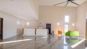 A spacious room with a marble floor, a reception desk, a ceiling fan, and a window providing natural light. - OYO Hotel Adairsville Calhoun South I-75 (Adairsville)