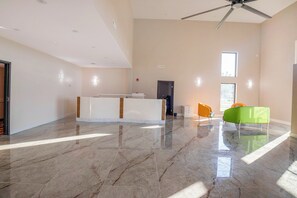 A spacious room with a marble floor, a reception desk, a ceiling fan, and a window providing natural light. - OYO Hotel Adairsville Calhoun South I-75 (Adairsville)