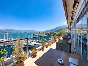 A balcony with a view of a marina, potted plants, and a table. - Dedeoglu Hotel (Fethiye)