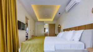 A hotel room with a bed, a television, a mirror, and a wooden headboard. - Dedeoglu Hotel (Fethiye)