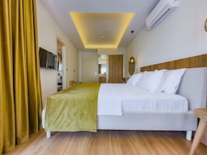 A hotel room with a bed, a television, a mirror, and a wooden headboard. - Dedeoglu Hotel (Fethiye)