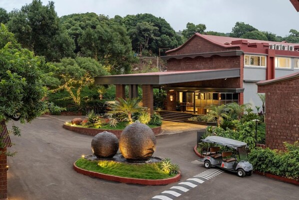 Un hotel con entrada cubierta, camino de entrada pavimentado y un carrito de golf.