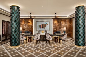 A lobby with a checkered floor, a central table with chairs, and two large columns with patterned designs. - Fountain Mahabaleshwar Ihcl Seleqtions (Mahabaleshwar)