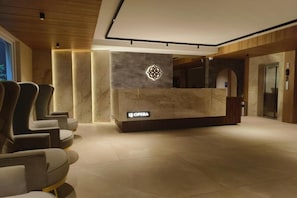 Una zona de recepción con mostrador de mármol, un logotipo y un cartel que dice 'LE OPERA'.