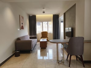 Uma sala de estar moderna com sofá, mesa de centro, poltrona e televisão.