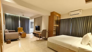 Ein modernes Hotelzimmer mit einem großen Bett, einer Couch, einem Schreibtisch und einem Fernseher.