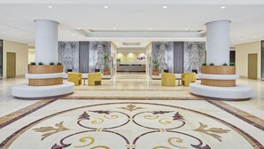 A hotel lobby with a marble floor, two large columns, and a reception desk in the background. - Nur Al Naseem by Makarem (Makkah)