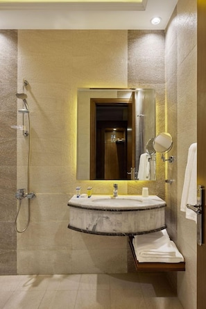 Un bany modern amb un lavabo de marbre, un vàter de mà i un mirall gran.