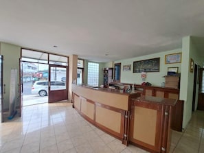 Un área de recepción con mostrador de madera, puerta de cristal y vista a la calle.
