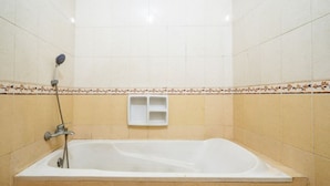 Casa de banho padrão de hotel com banheira, chuveiro e sanita.