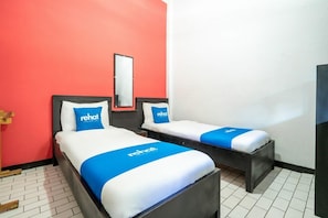 Habitació d'hotel amb dos llits, cada un amb un llençol i coixins blaus i blancs a conjunt.