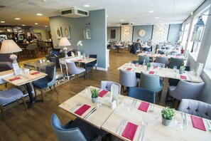 A spacious restaurant with multiple dining tables, chairs, and a bar area. - The Wiltshire Hotel, Golf & Leisure (Swindon)
