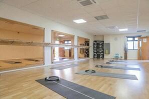 A spacious room with wooden flooring, exercise mats, and a mirrored wall. - The Wiltshire Hotel, Golf & Leisure (Swindon)