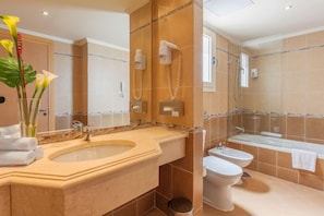 Une salle de bain comprenant un grand lavabo, un bidet, une baignoire et des toilettes.