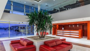 A modern lobby with a reception desk, red sofas, and a large indoor plant. - Cleopatra Luxury Resort Makadi Bay-adults Only 16 (Makadi Bay)