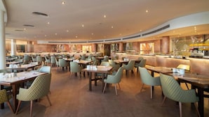 A spacious dining area with multiple tables and chairs, a central bar, and a modern ceiling design. - Cleopatra Luxury Resort Makadi Bay-adults Only 16 (Makadi Bay)