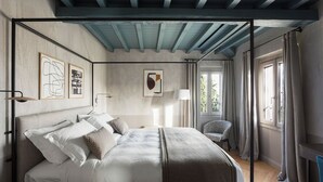 Ein Schlafzimmer mit Himmelbett, einem Sessel, einem Schreibtisch und Kunstwerken an den Wänden.