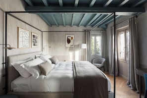 A bedroom with a four-poster bed, a chair, a desk, and artwork on the walls. - Roncolo 1888 (Quattro Castella)