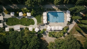 Ein Luftbild eines Resorts mit Schwimmbad, Sonnenschirmen und einem angelegten Garten.