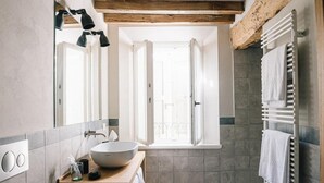 Ein Badezimmer mit einem großen Spiegel, einem hölzernen Waschtisch, einem weißen Waschbecken und einem Handtuchhalter.