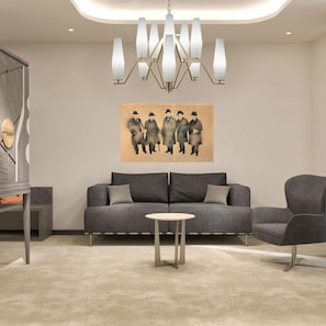 A modern living room with a grey sofa, a round coffee table, and a chandelier. - Hotel Via Veneto (Rome)