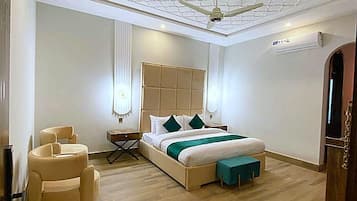 Un dormitorio moderno con una cama grande, un ventilador de techo y piso de madera.