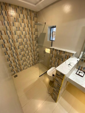 Un baño con pared de baldosas estampadas, cabina de ducha de vidrio y encimera de mármol.