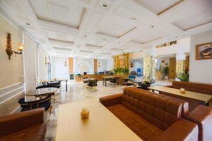 A hotel lobby with a central seating area, tables, and a decorative wall. - Grand Shalimar Hotel (Multan)