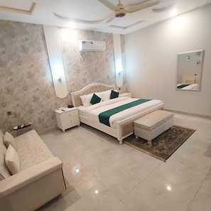 Un dormitorio con cama, mesitas de noche, cómoda, ventilador de techo, equipo de aire acondicionado y espejo.