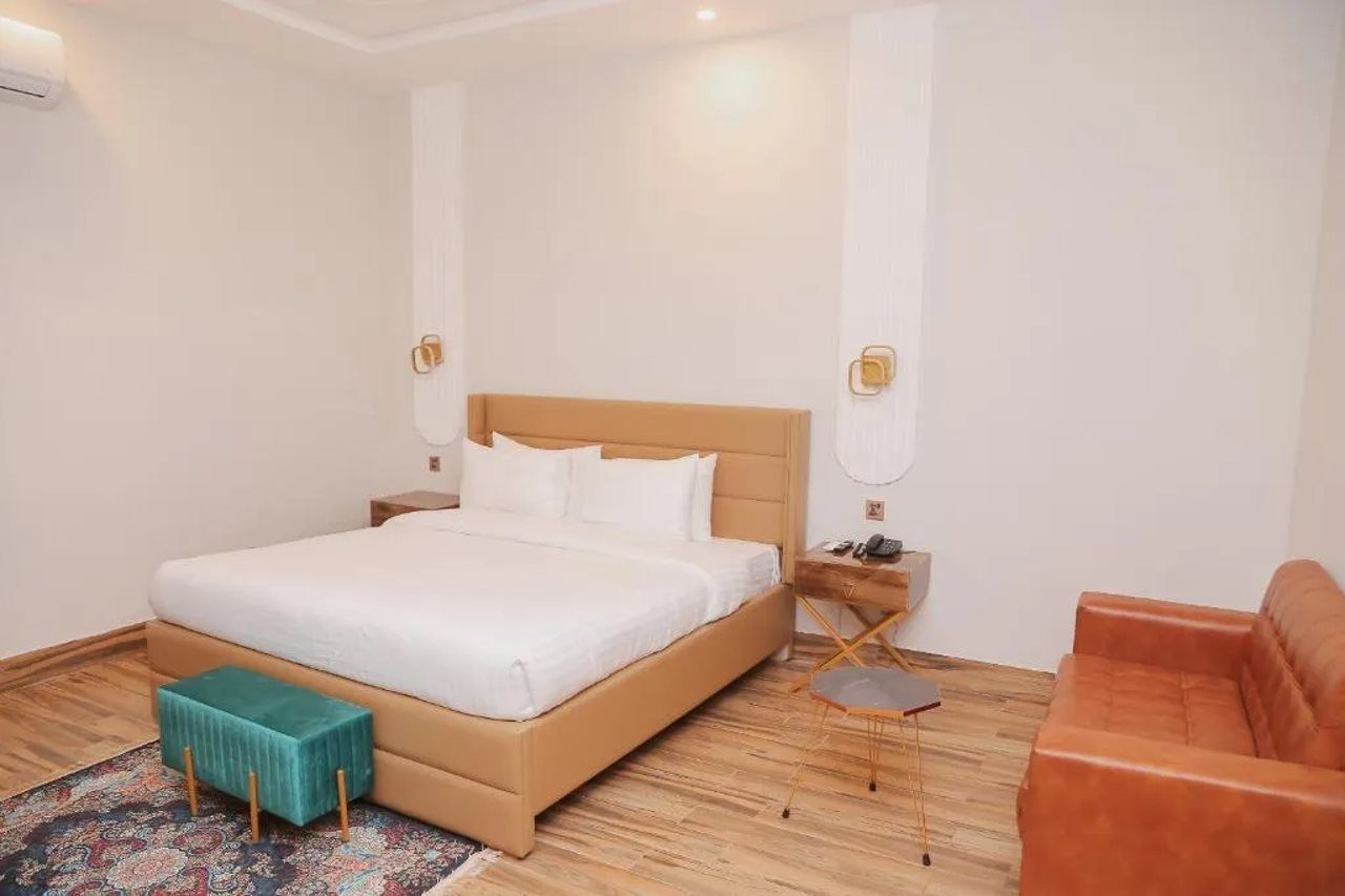 Una habitación de hotel con una cama, una mesita, una silla y un sofá.