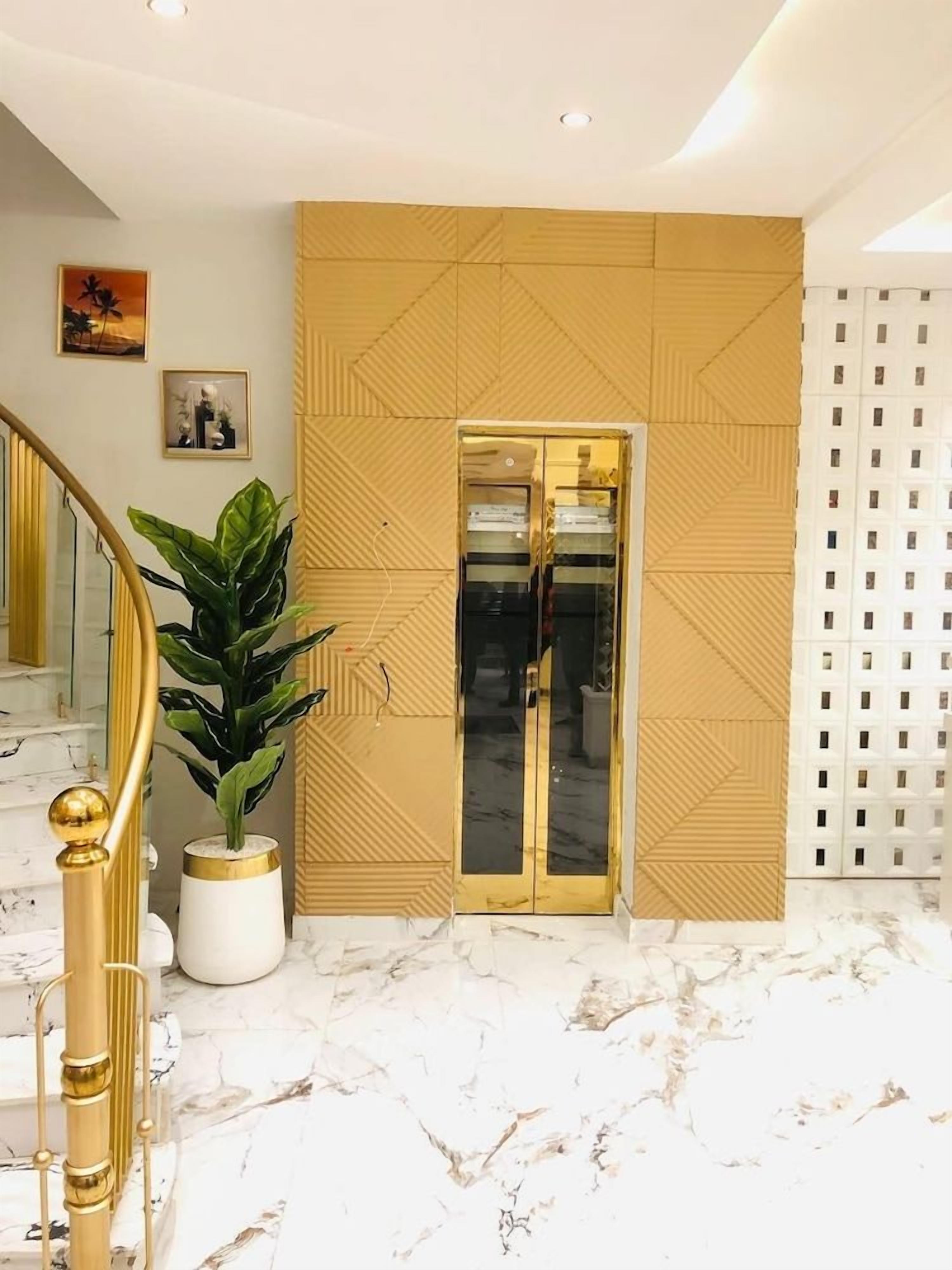Ein modernes Interieur mit Marmorboden, einer goldenen Treppe, einer Pflanze und einem geometrischen Wanddesign.