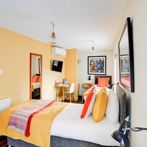 A hotel room with a bed, bedside table, desk, chair, and a television on the wall. - Dancenter Southwark Near London Bridge (London)