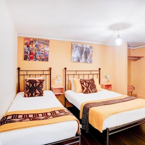 A hotel room with two beds, each with a patterned pillow and a blanket. There are wall art pieces above the beds and a ceiling light fixture. - Dancenter Southwark Near London Bridge (London)