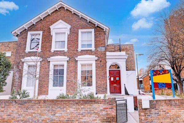 A brick building with a red door, white windows, and a sign indicating 'Queen Road.' - Dancenter Southwark Near London Bridge (London)