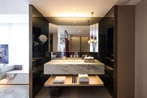 Un baño moderno con un espejo grande, encimera de mármol y tocador de madera.