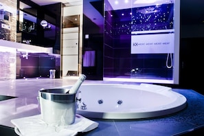 A modern bathroom with a large bathtub, a glass-enclosed shower, and a visible brand name on the shower wall. - Carretera Valencia km. 13,2 (Cadrete)