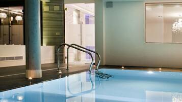 Una piscina interior moderna con fondo de vidrio transparente, barandilla metálica y diseño minimalista.