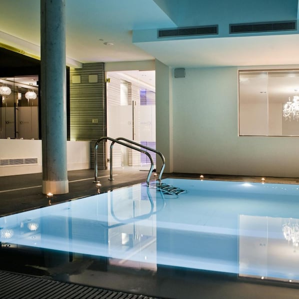 A modern indoor swimming pool with a clear glass bottom, a metal handrail, and a minimalist design. - Carretera Valencia km. 13,2 (Cadrete)