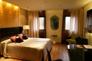 A hotel room with a large bed, a desk, a chair, a mirror, and curtains. - Carretera Valencia km. 13,2 (Cadrete)
