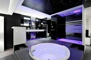A modern bathroom with a central jacuzzi, mirrored walls, and a sleek design. - Carretera Valencia km. 13,2 (Cadrete)