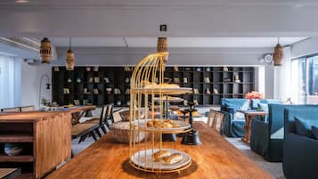 A modern interior with a wooden dining table, a three-tiered dessert stand, and a bookshelf in the background.