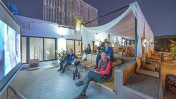 An outdoor seating area with a modern design, including a large screen for presentations and comfortable seating arrangements.