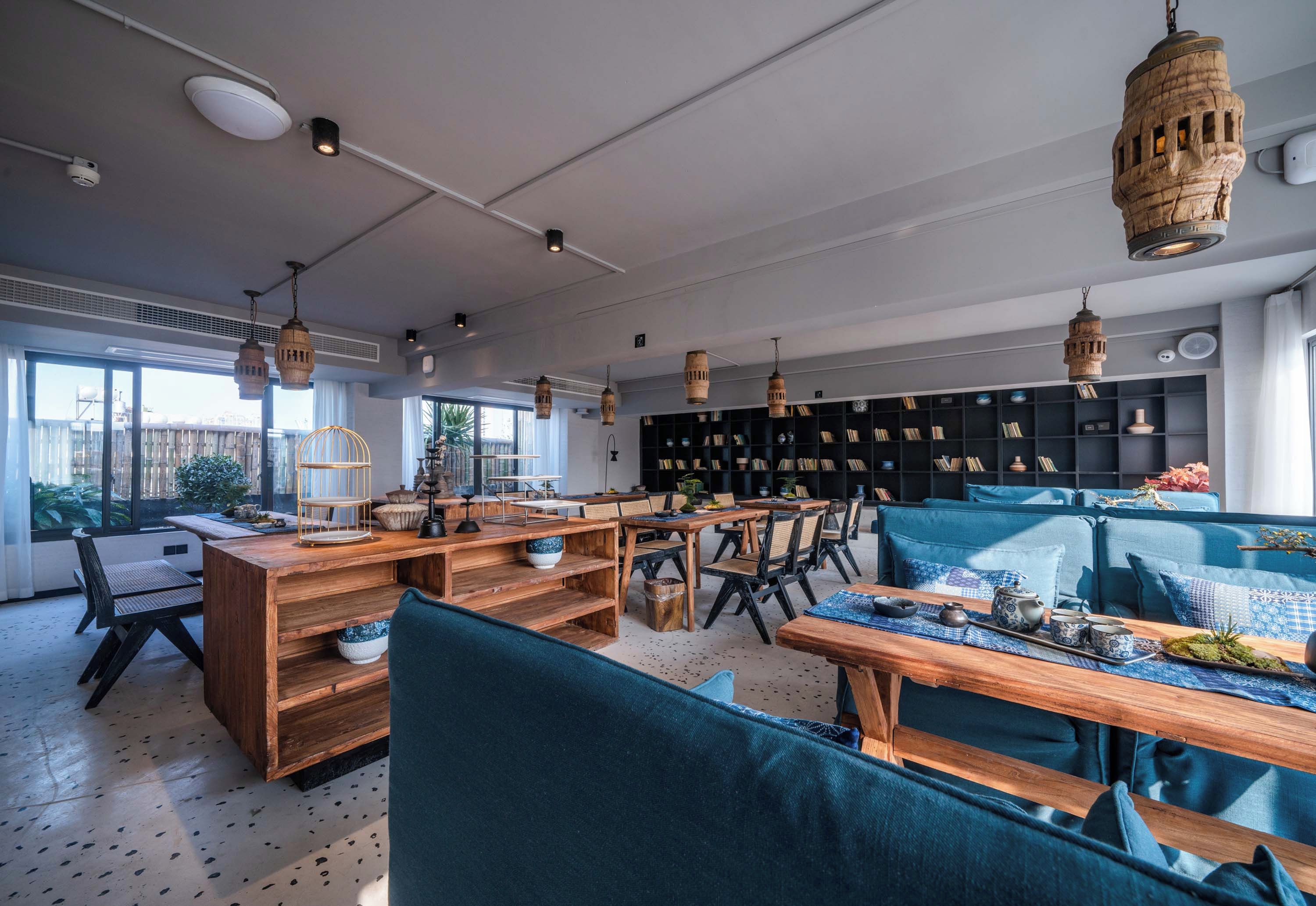 A modern interior with wooden furniture, hanging lights, and a large bookshelf.