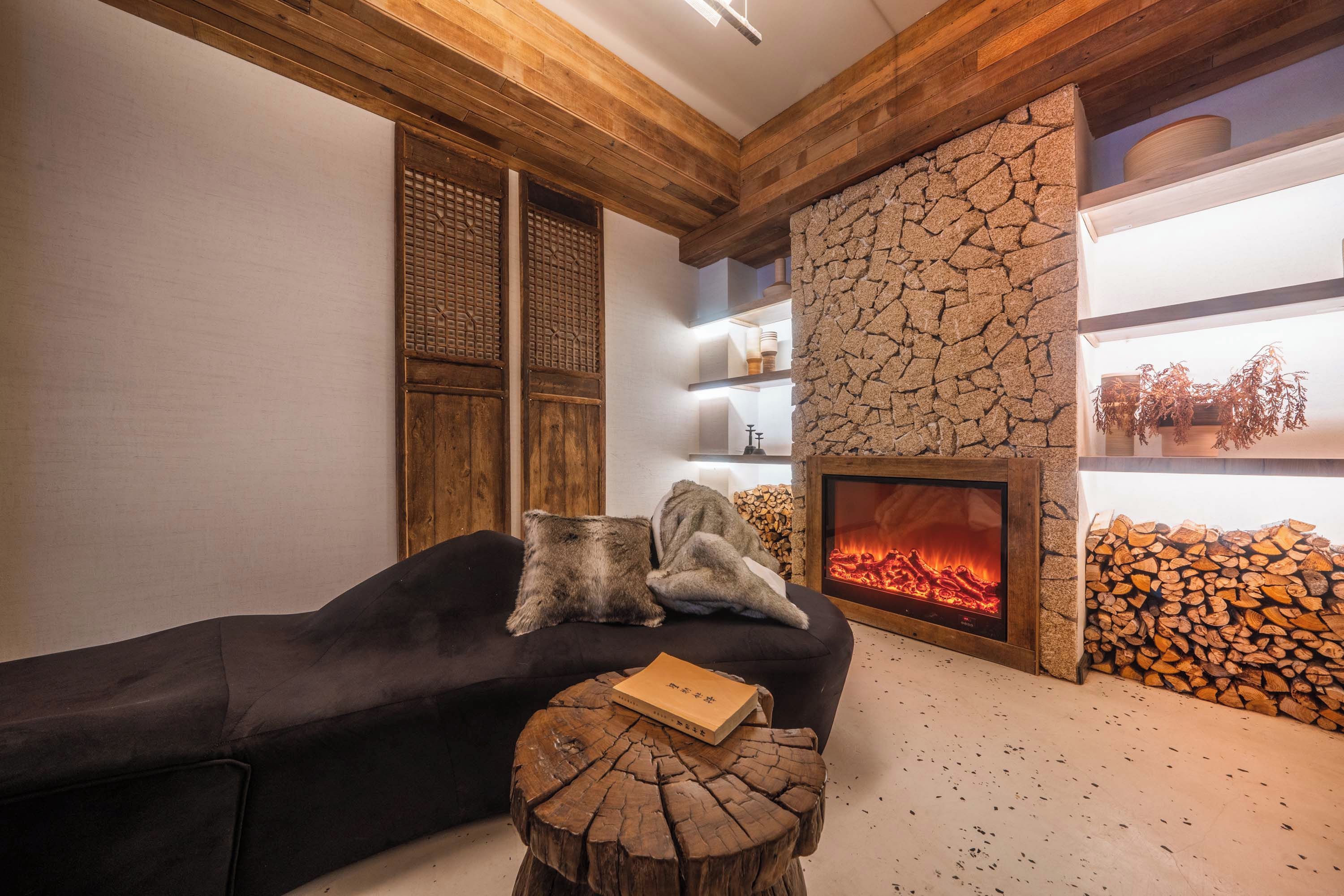 Una sala de estar acogedora con chimenea, vigas de madera y una pared de piedra.