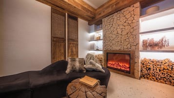 Una sala de estar acogedora con chimenea, vigas de madera y una pared de piedra.