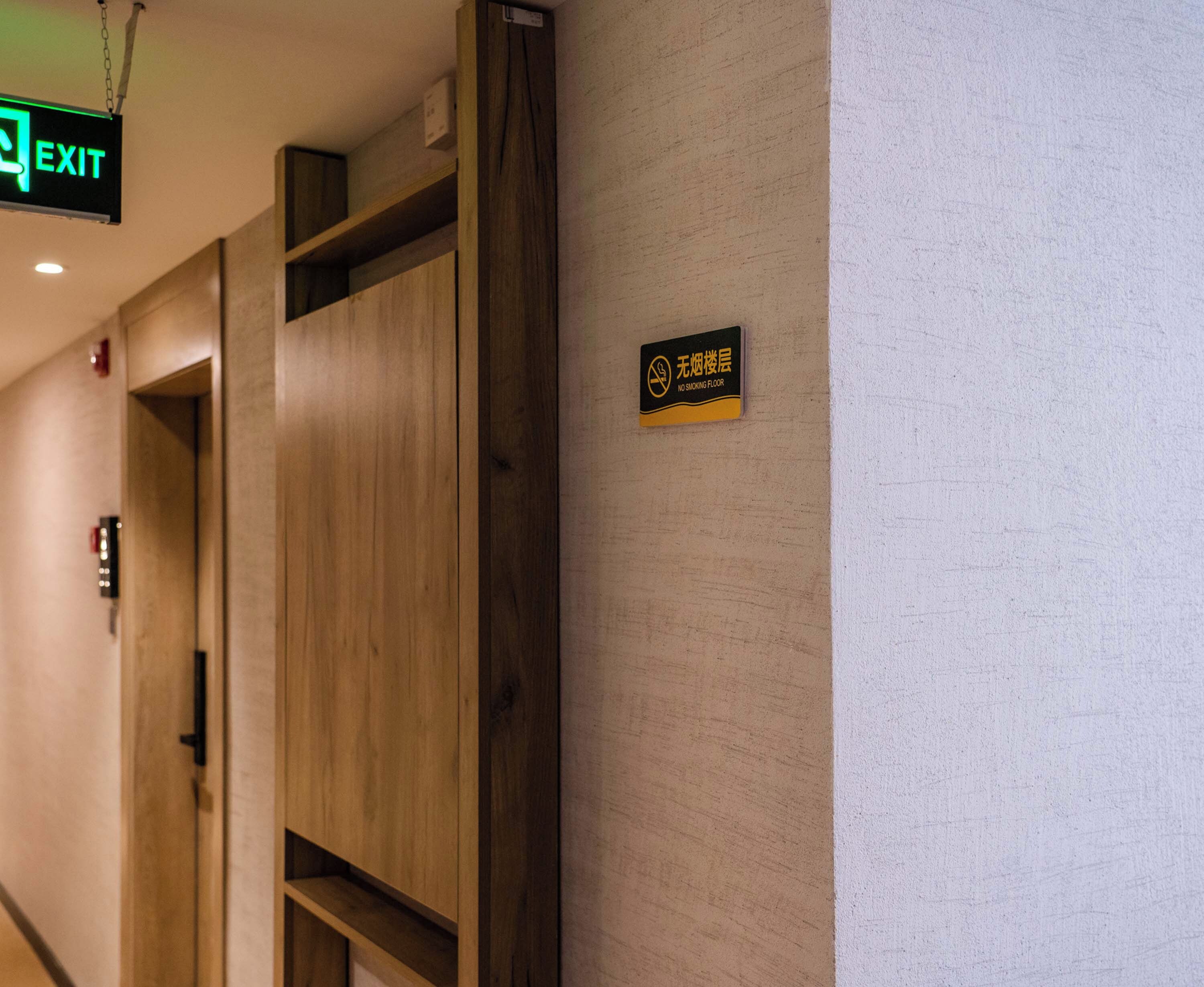 A hallway with wooden paneling, an exit sign, and a no-smoking floor sign.