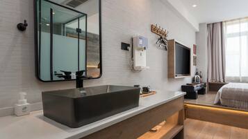 Un baño moderno con un espejo grande, un lavamanos negro y un mueble de tocador con gabinete de madera.