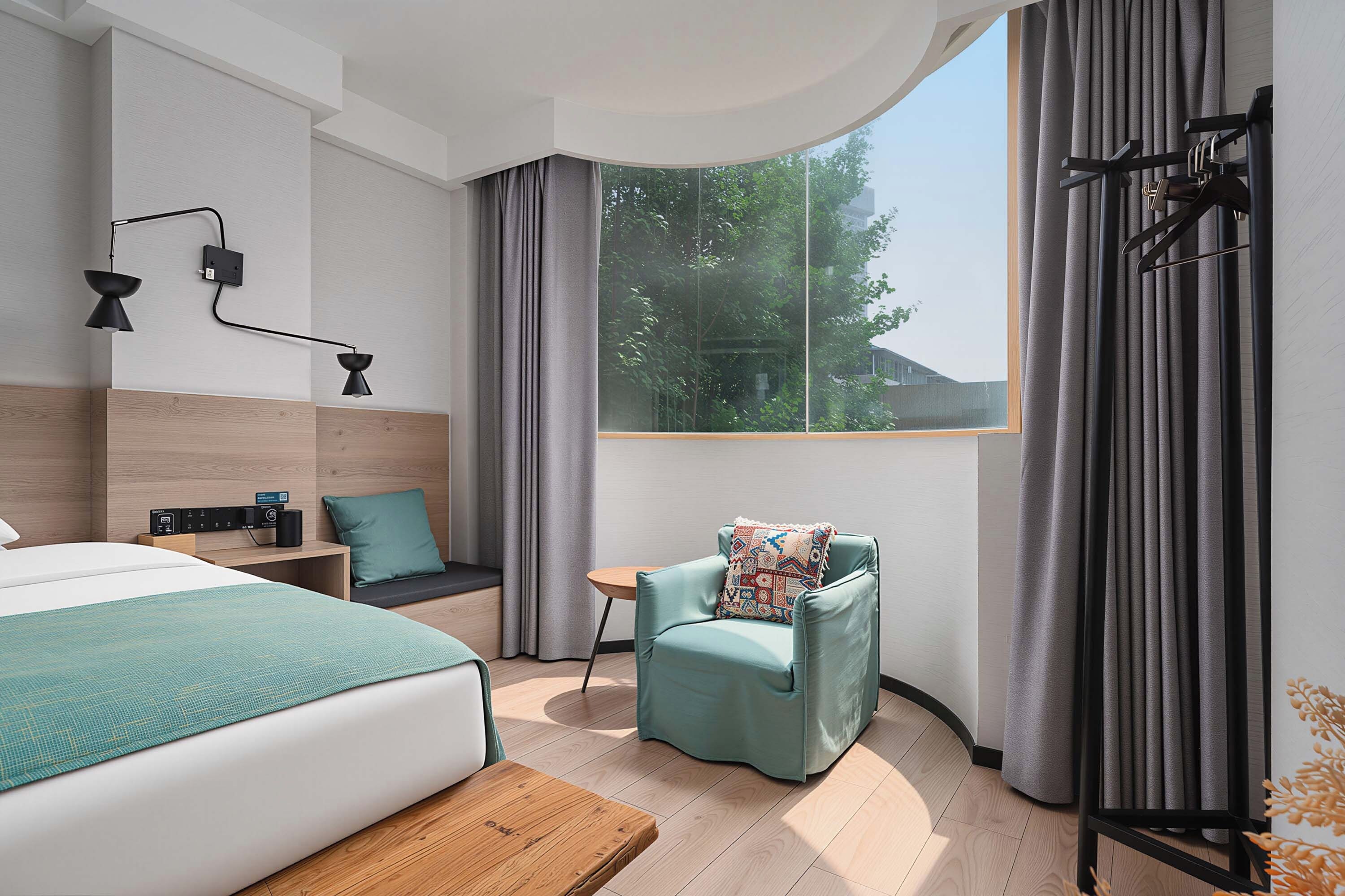 Una camera d'albergo moderna con un letto, una zona salotto con una poltrona e un tavolino, una finestra con tende e una lampada a parete.
