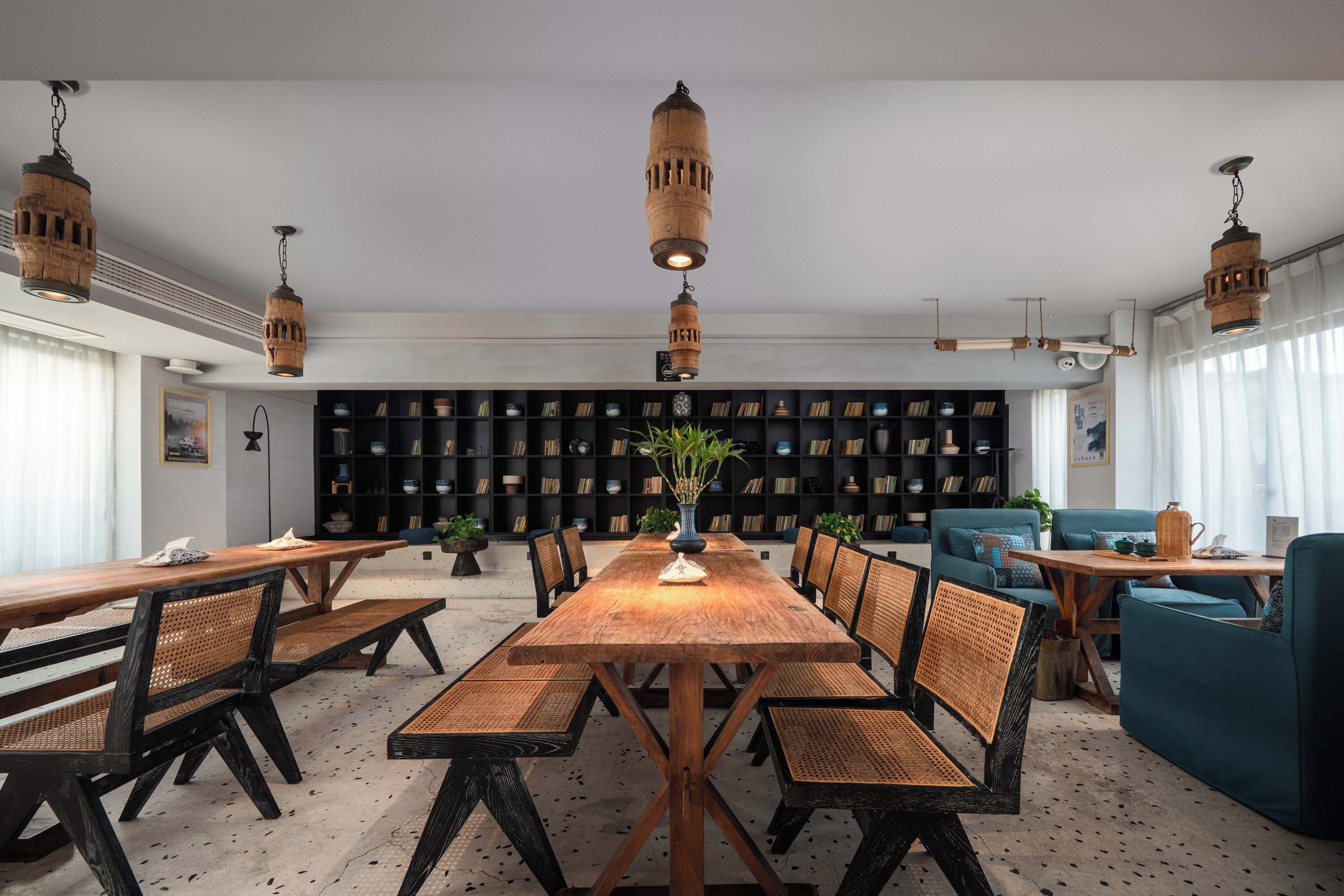 A spacious room with a long wooden table and chairs, surrounded by bookshelves filled with books and decorative items.