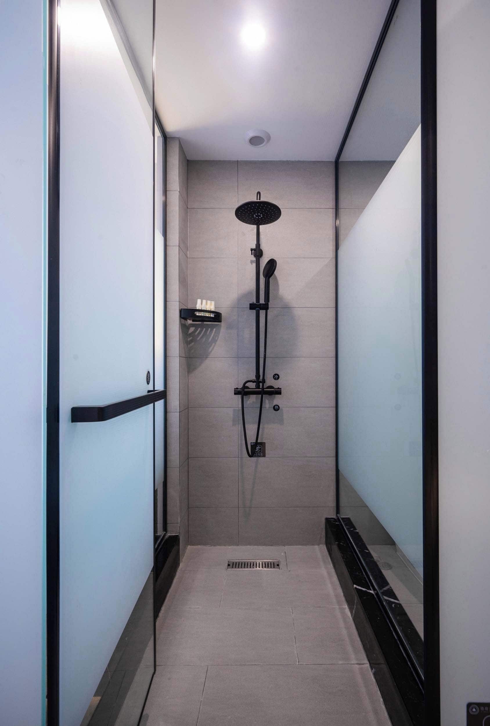 A modern shower stall with a handheld showerhead, a towel rack, and a control panel.